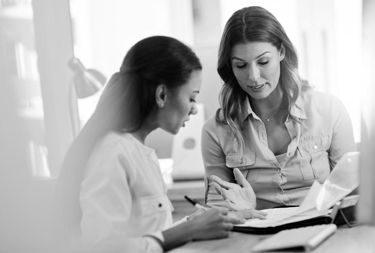 Woman looks at paperwork with female adviser